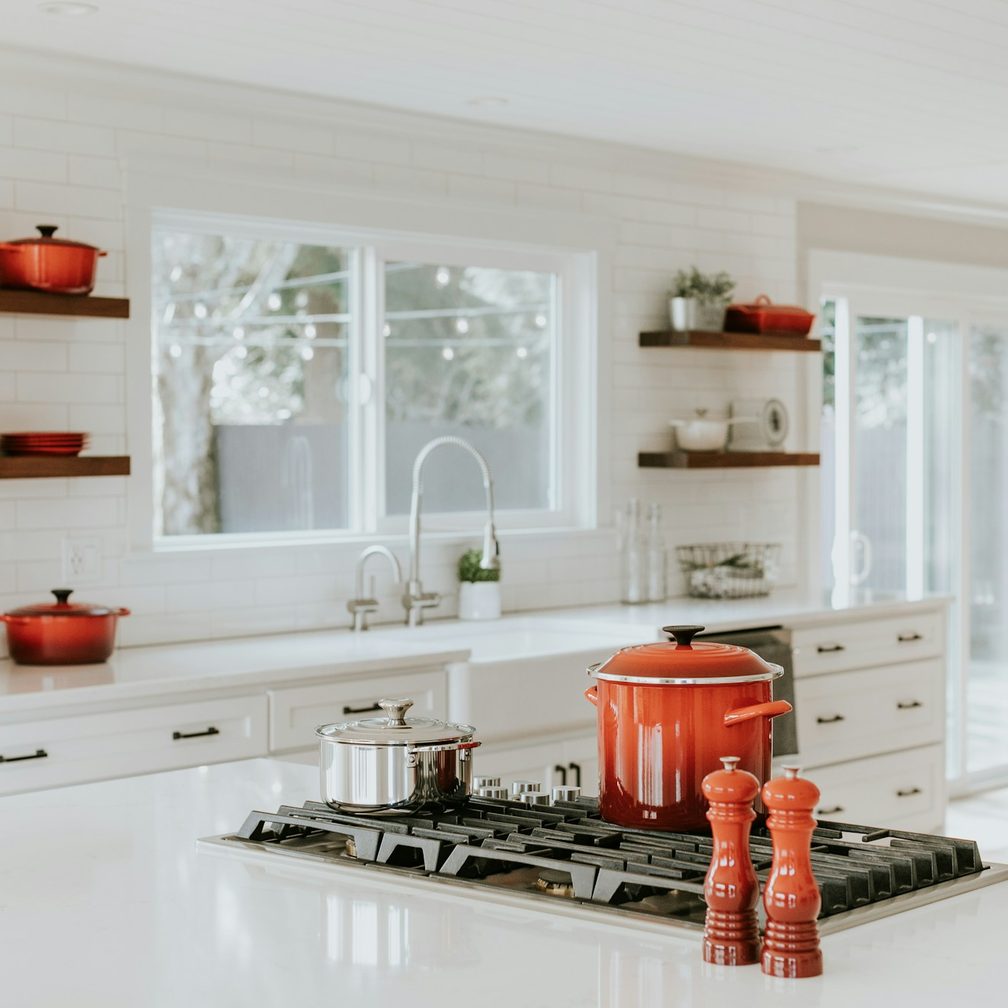 A tidy home kitchen with pots on the stove and a window above the sink